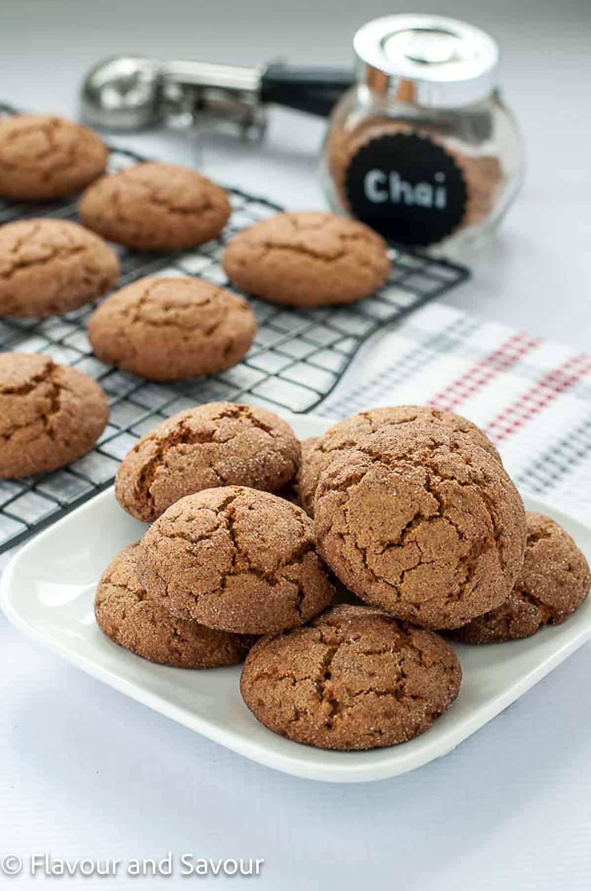 A plate full of chai-spiced gluten-free snickerdoodles with more on a cooling rack in the background.