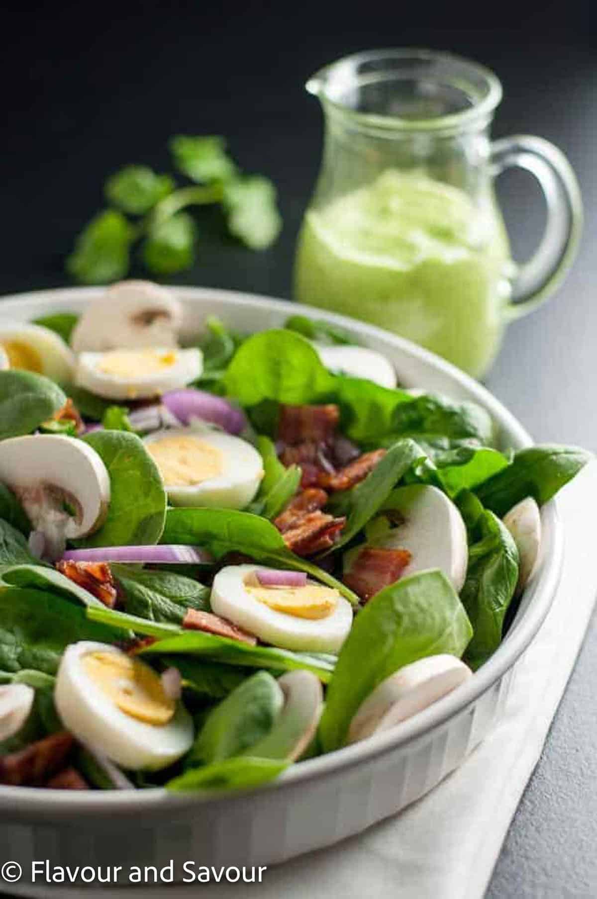 Spinach salad with hard boiled eggs, bacon and mushrooms.