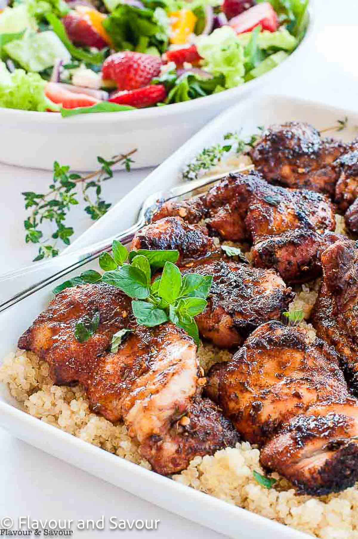 A platter of grilled cajun chicken thighs on a bed of quinoa.