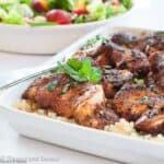 Square image of grilled chicken thighs with Cajun seasoning served on quinoa.