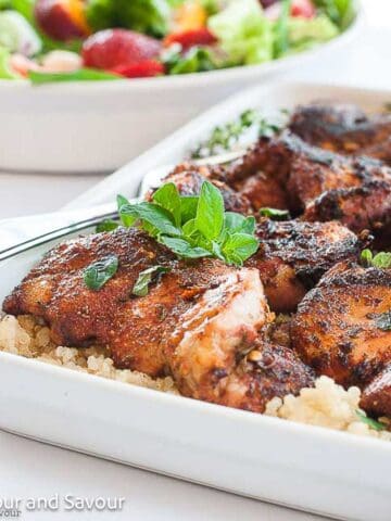 Square image of grilled chicken thighs with Cajun seasoning served on quinoa.