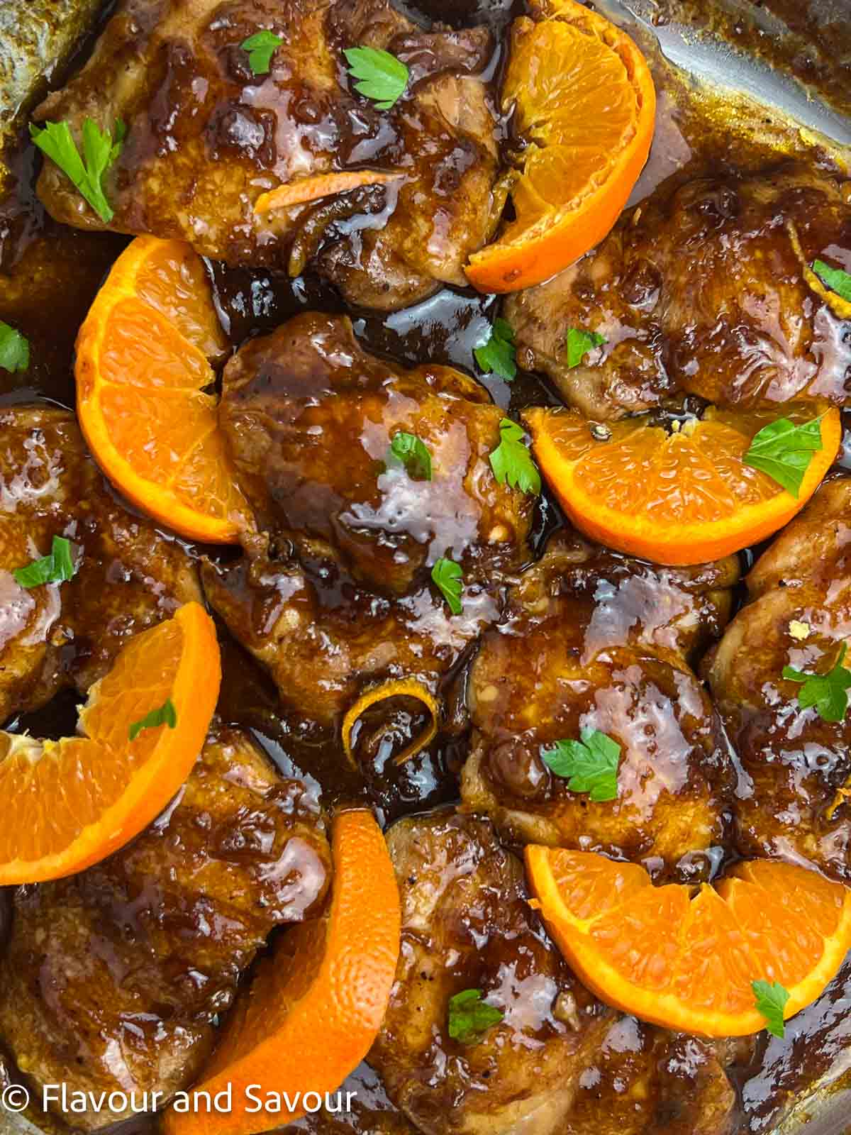 Glazed chicken thighs with hoisin sauce and sliced oranges.