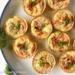 Mini crustless smoked salmon quiche on a plate garnished with fresh dill.