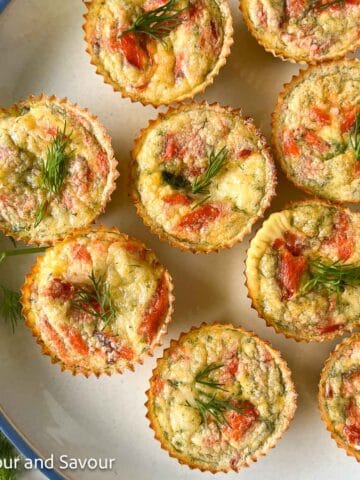 Mini crustless smoked salmon quiche on a plate garnished with fresh dill.
