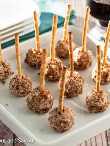Square image of mini goat cheese balls with pretzel sticks.