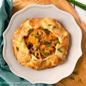 Potato galette with bacon and cheese made with almond flour pastry on a plate, garnished with chives.