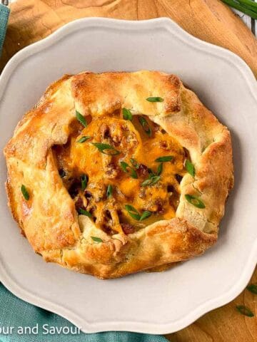 Potato galette with bacon and cheese made with almond flour pastry on a plate, garnished with chives.
