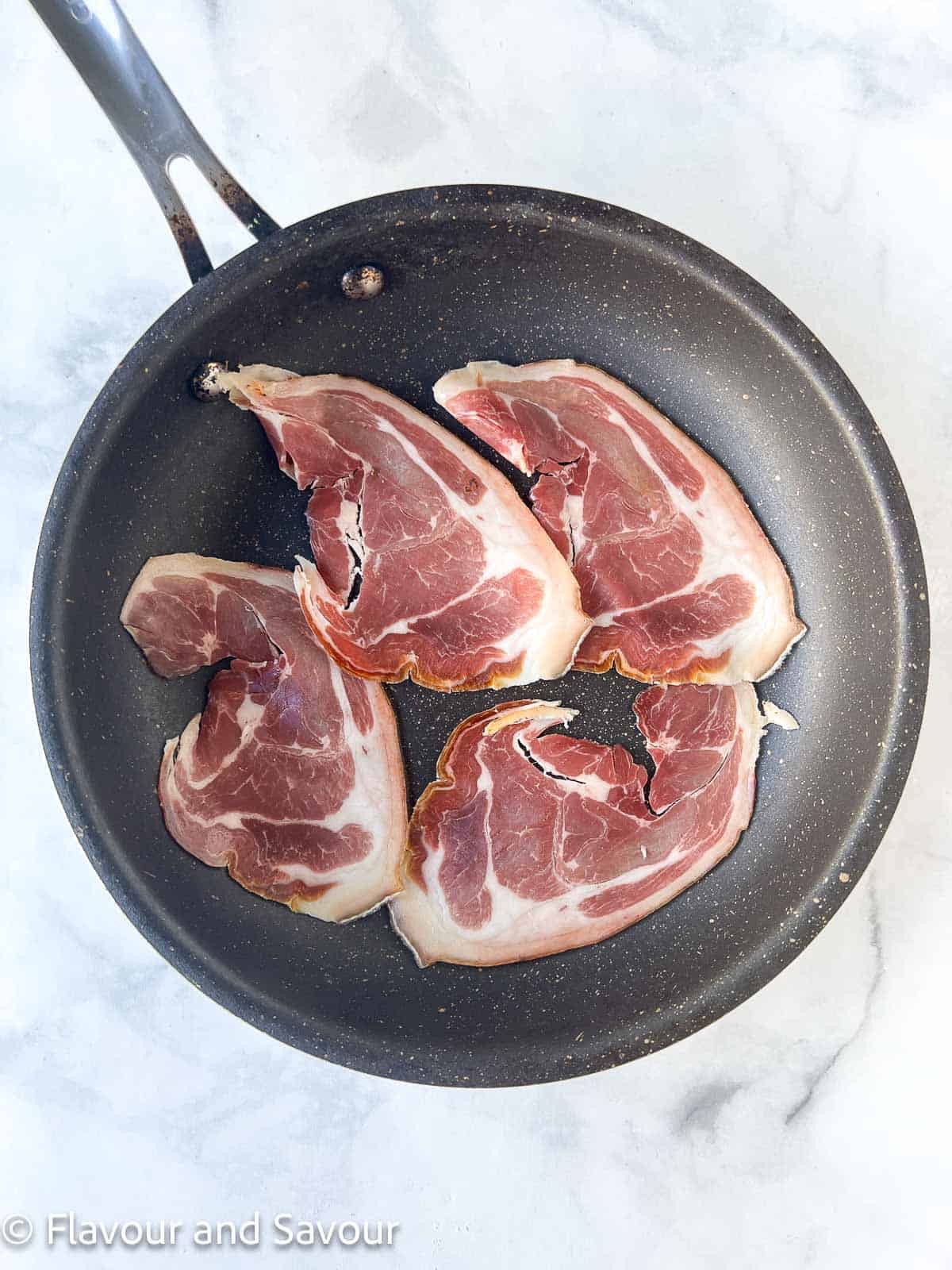 Prosciutto slices in a skillet.