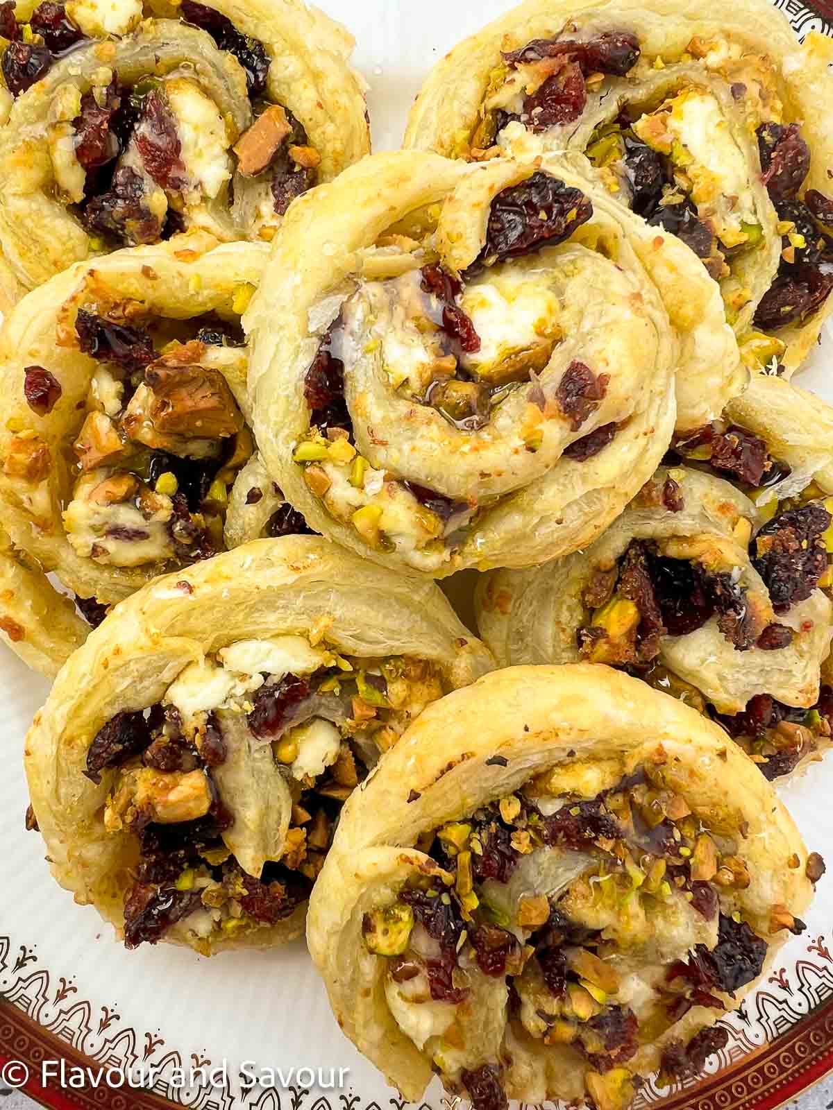 Cranberry Goat Cheese Puff Pastry PInwheels overlapped on a plate and drizzled with honey.