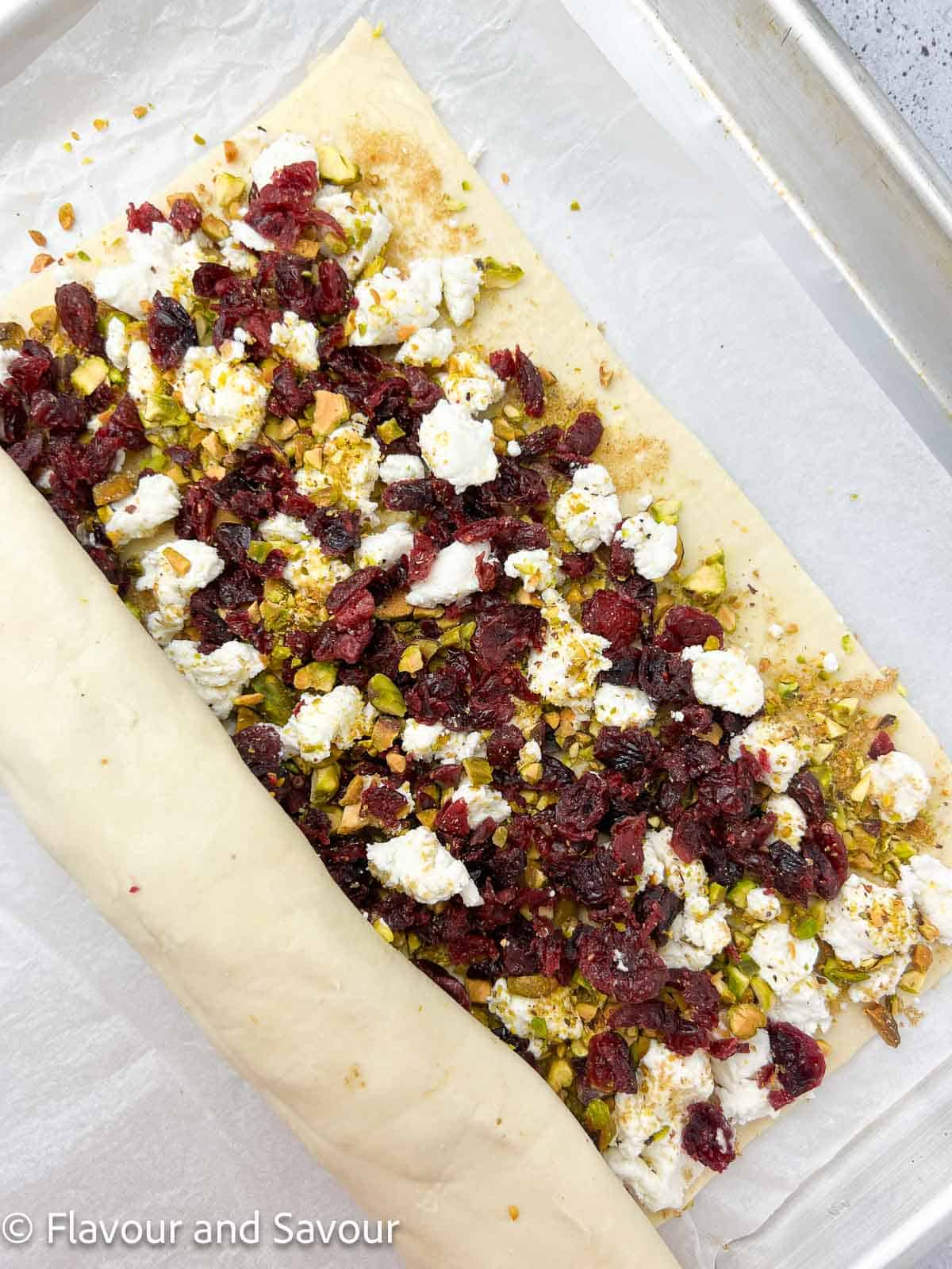 A half rolled log of puff pastry filled with goat cheese, dried cranberries and pistachios.