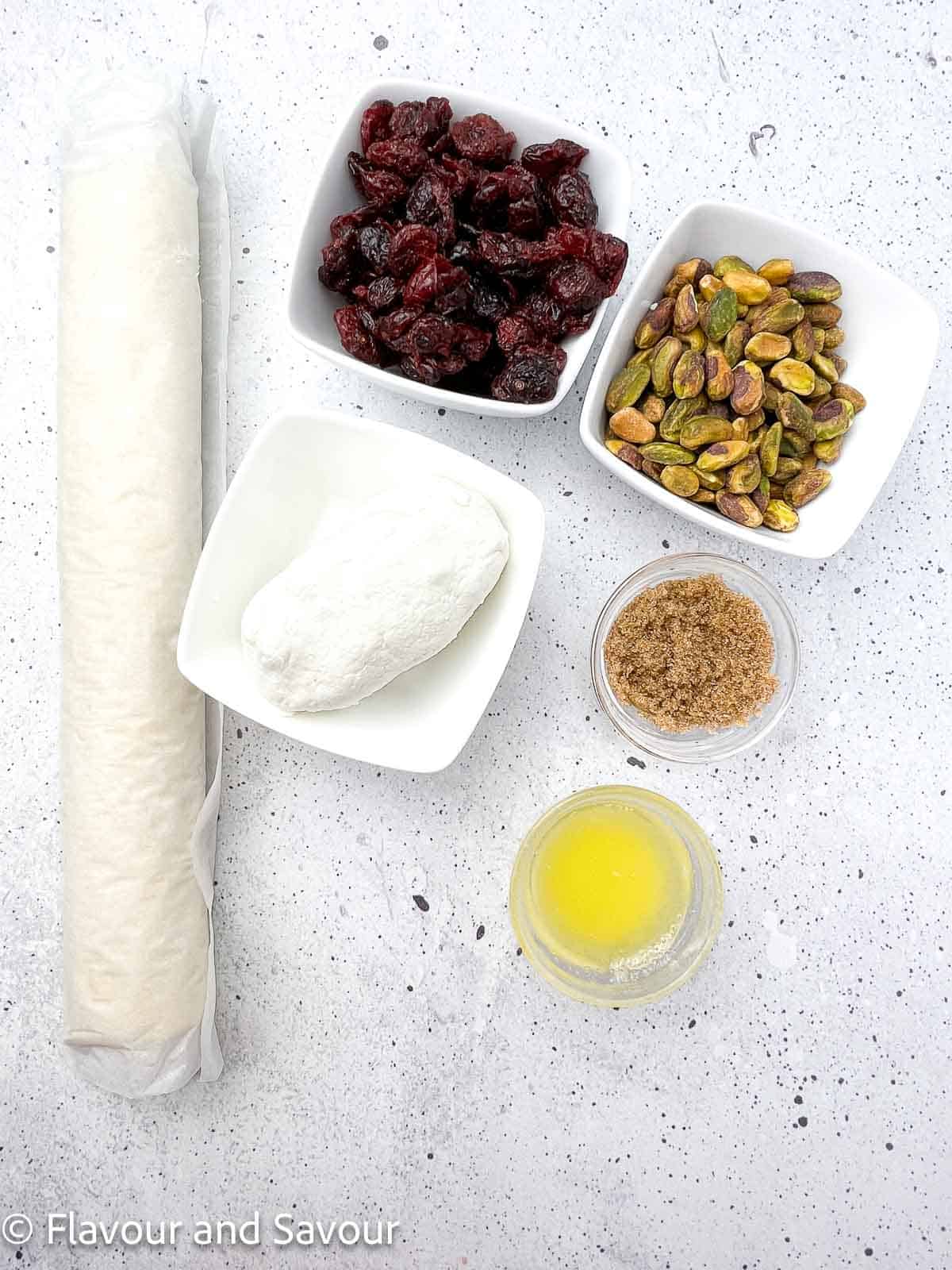 Ingredients for puff pastry cranberry pistachio pinwheels: puff pastry, dried cranberries, pistachios, goat cheese, brown sugar, and melted butter.