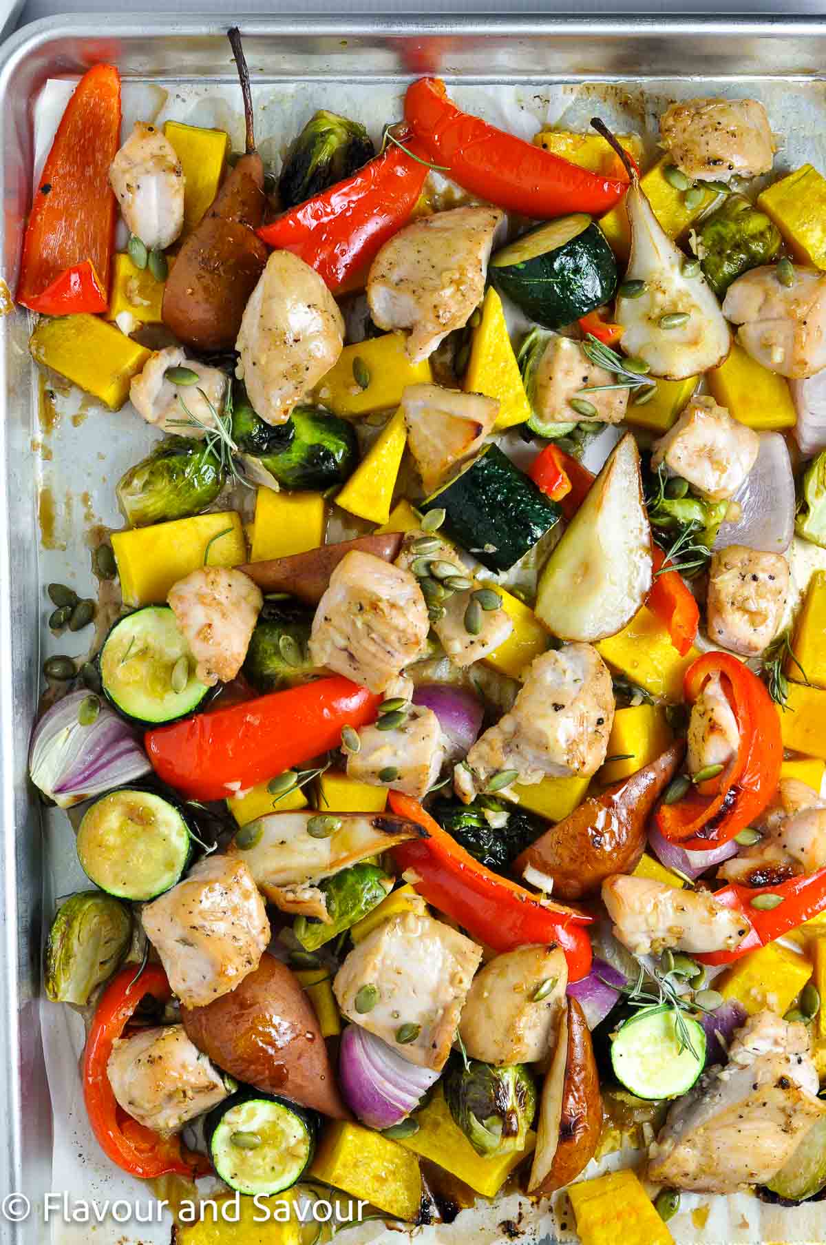Cooked sheet pan dinner with maple garlic chicken cubes and seasonal vegetables.