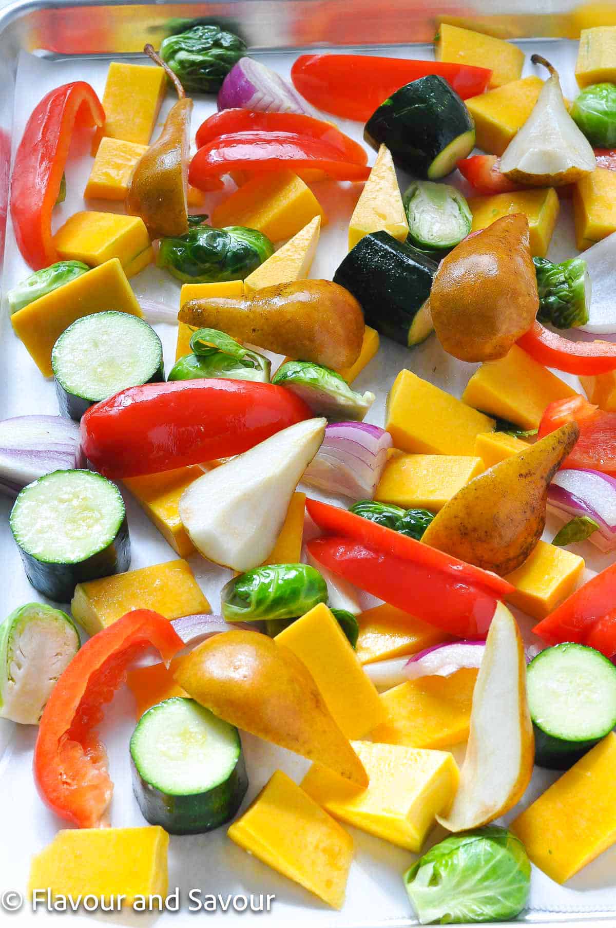 Chopped vegetables for maple garlic chicken sheet pan dinner on a sheet pan.