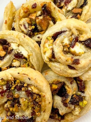 Cranberry Pistachio Puff Pastry PInwheels overlapping on a plate.