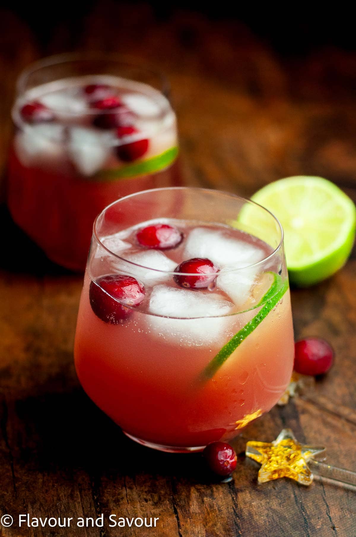 Two short glasses of sparkling cranberry holiday punch with lime slices and cranberries.