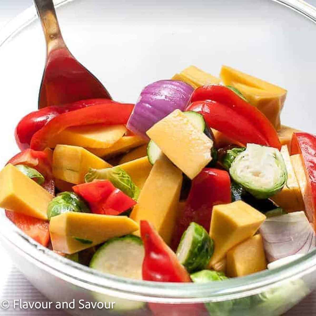 Vegetables for chicken sheet pan dinner in a bowl tossed with olive oil.