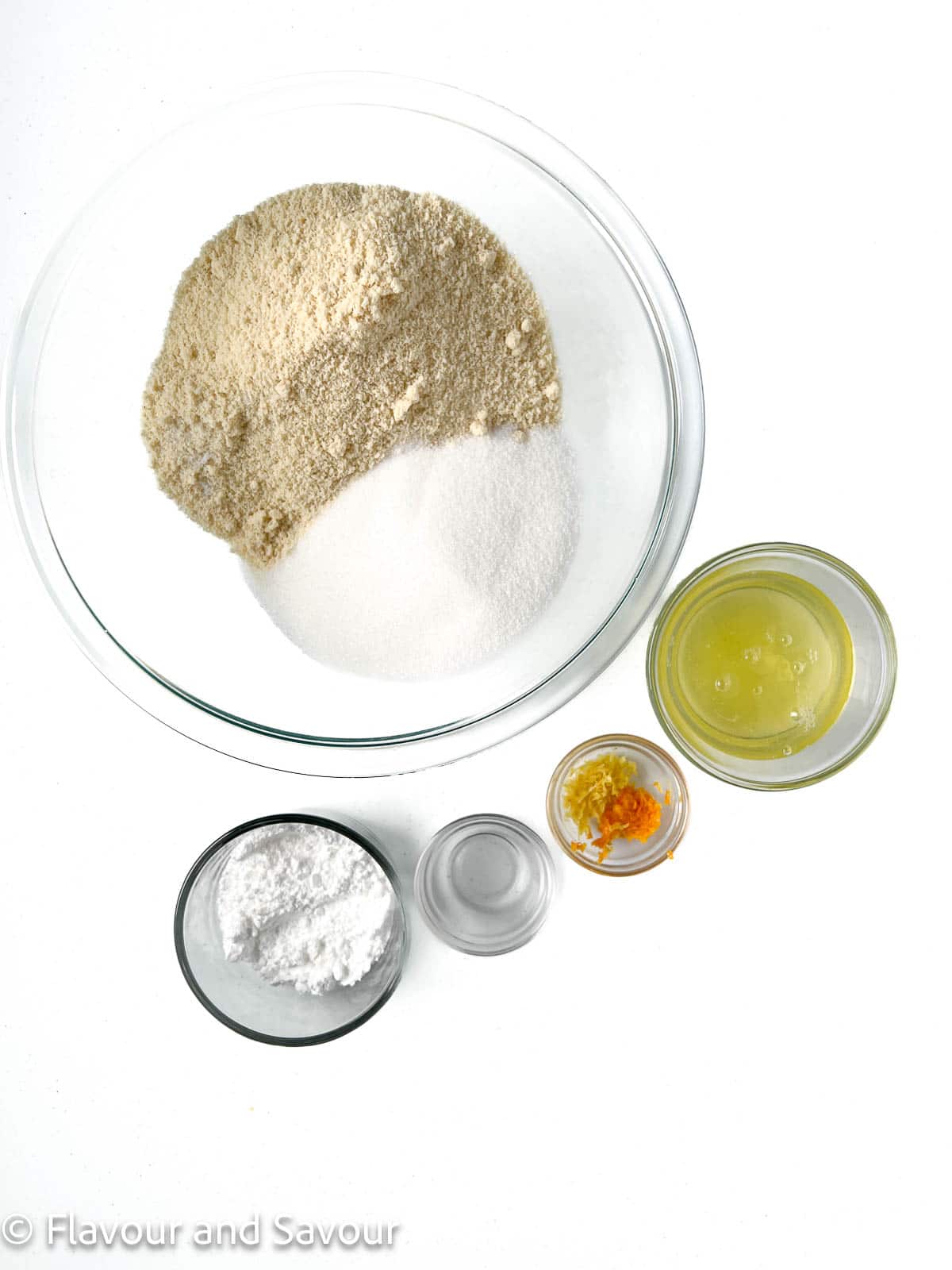 Ingredients for Italian almond cookies: almond flour, sugar, salt, egg whites, lemon and orange zest, almond extract, and confectioner's sugar.