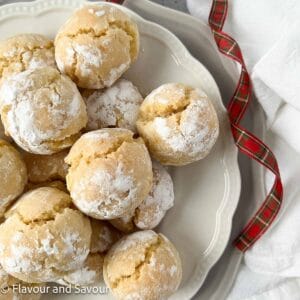 Amaretti or Italian almond cookies on a plate with a red plaid ribbon.