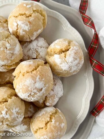 Amaretti or Italian almond cookies on a plate with a red plaid ribbon.