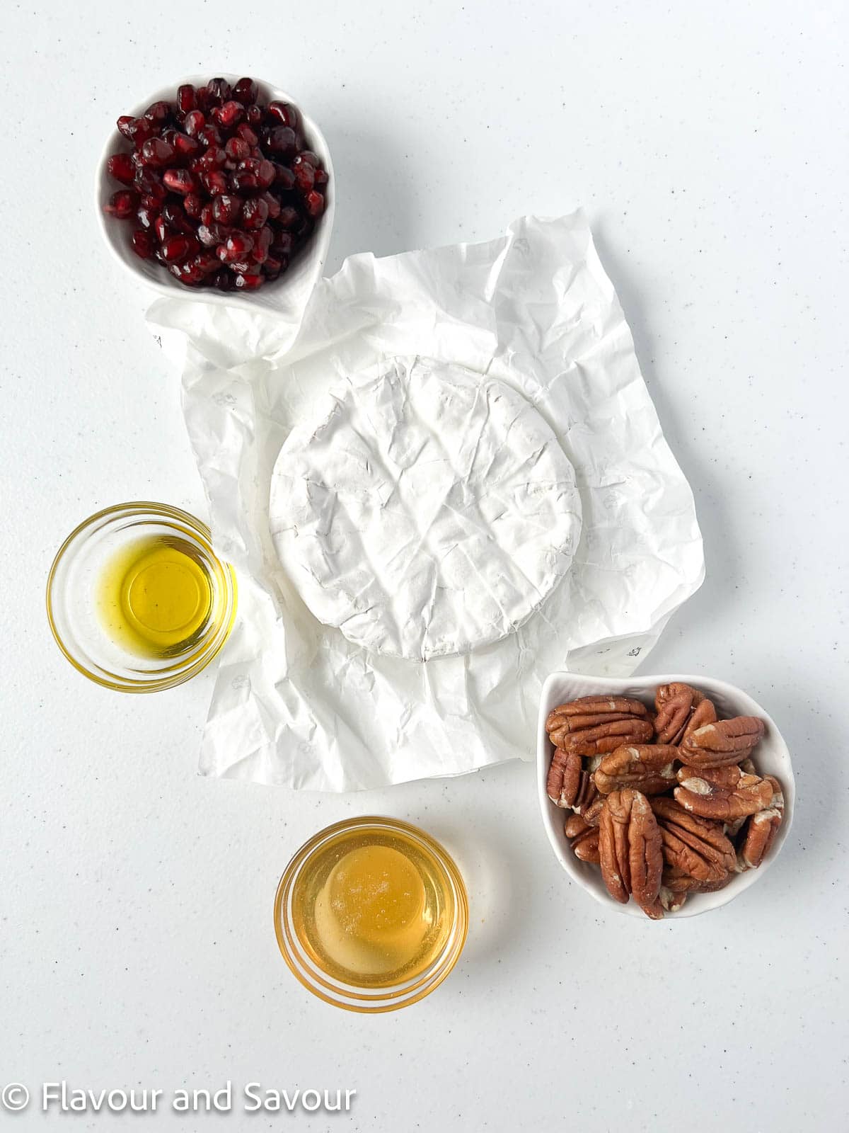 Ingredients for baked Brie: Brie cheese, pomegranates, pecans, honey or hot honey and olive oil.