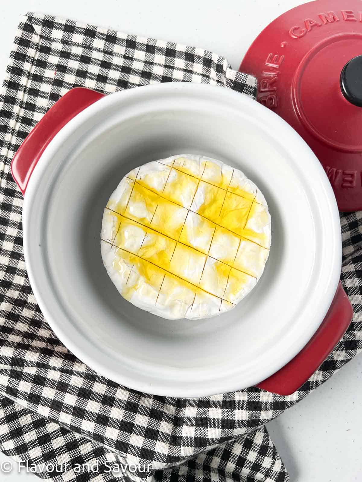 A round of Brie in a baking dish topped with olive oil.