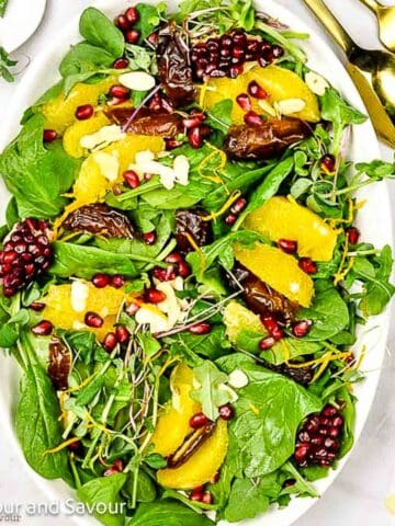 A green salad with orange sections, Medjool dates and pomegranates.