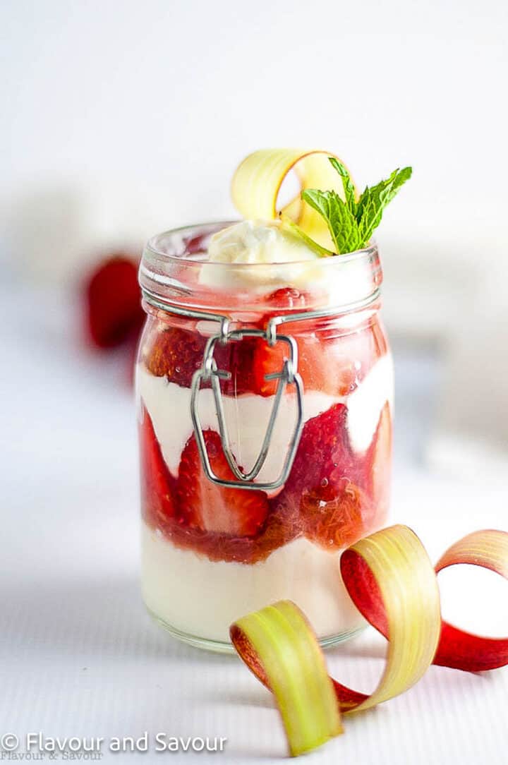 Strawberry rhubarb parfait in a jar, showing layers of yogurt, fresh strawberries and rhubarb compote.