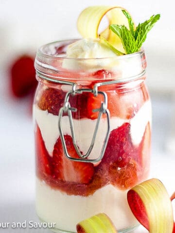 Strawberry rhubarb parfait layered with rhubarb compote and yogurt in a jar.