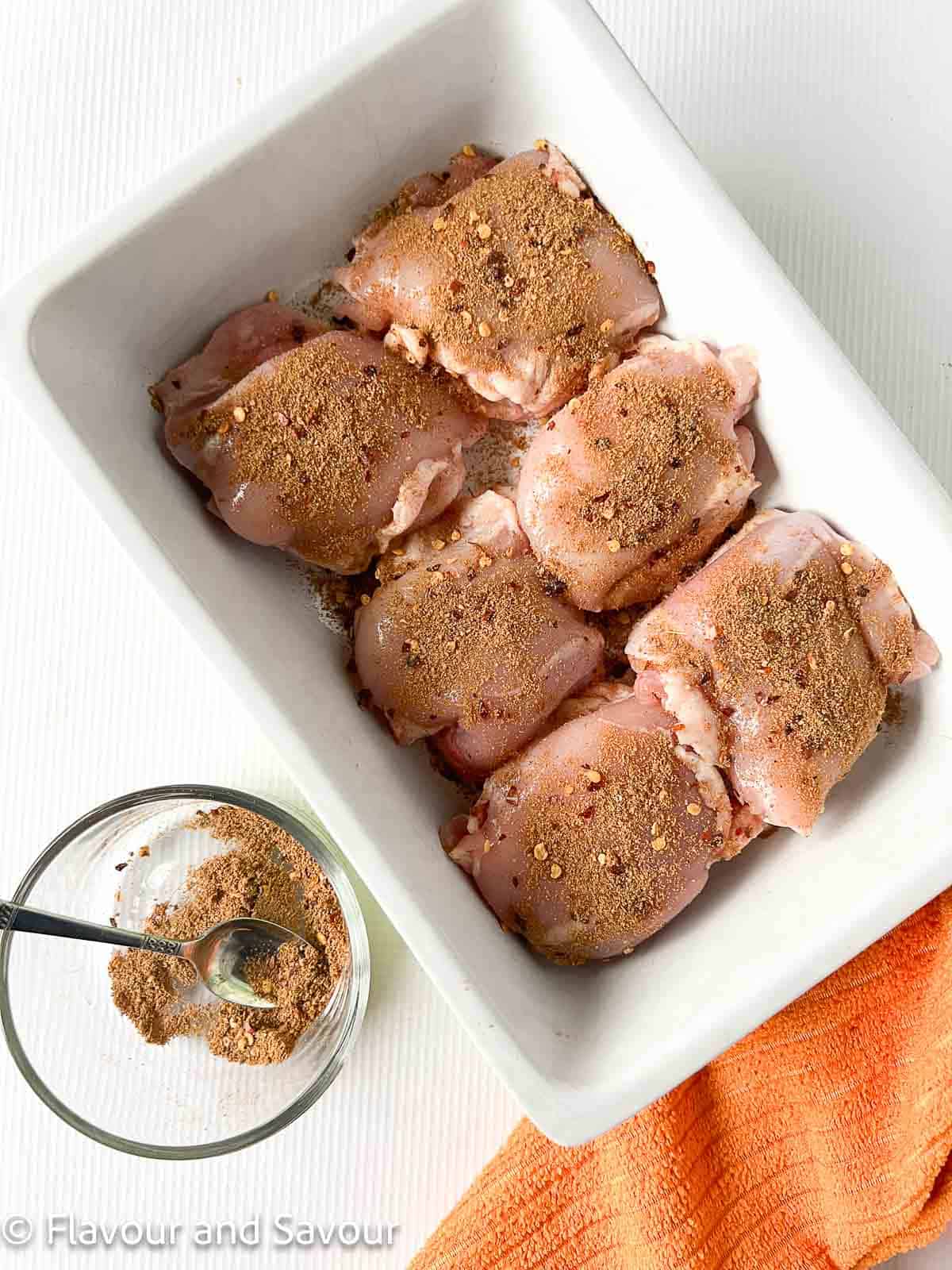 Raw chicken thighs sprinkled with Moroccan spices.