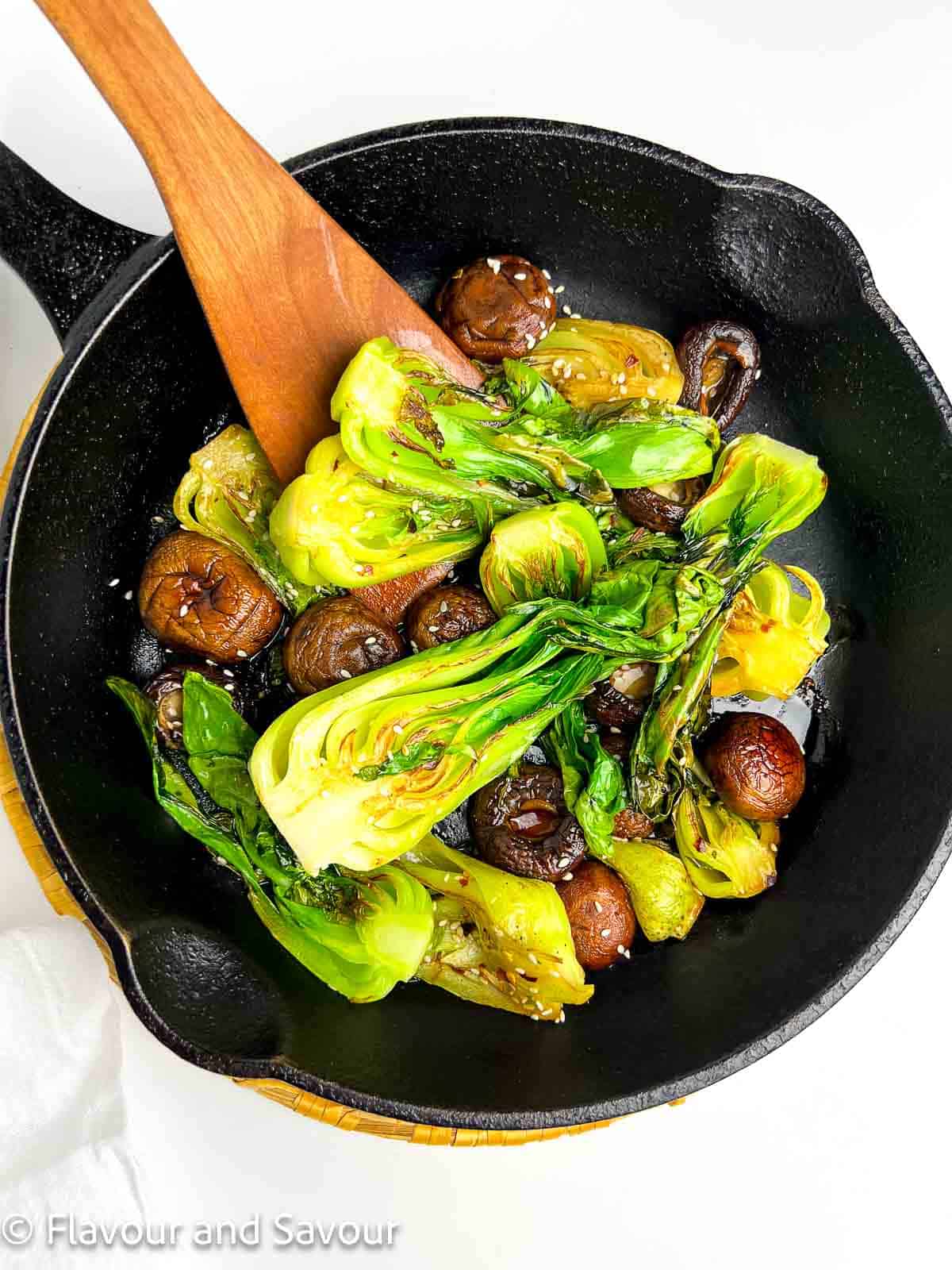 Shanghai bok choy and mushrooms with stir fry sauce in a cast iron skillet.