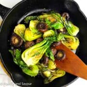 Baby bok choy and mushroom stir fry in a cast iron skillet.