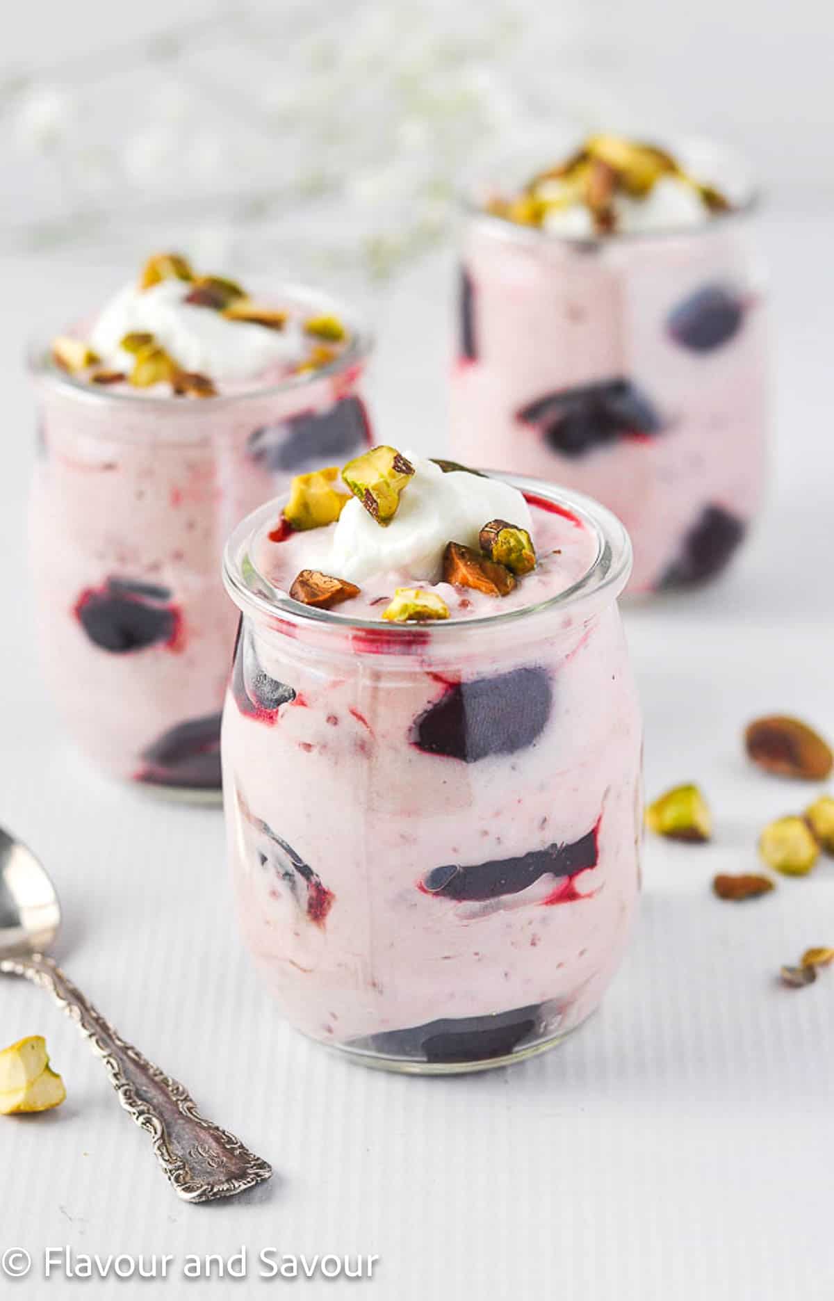 Three small dessert glasses filled with light cherry coconut fool.