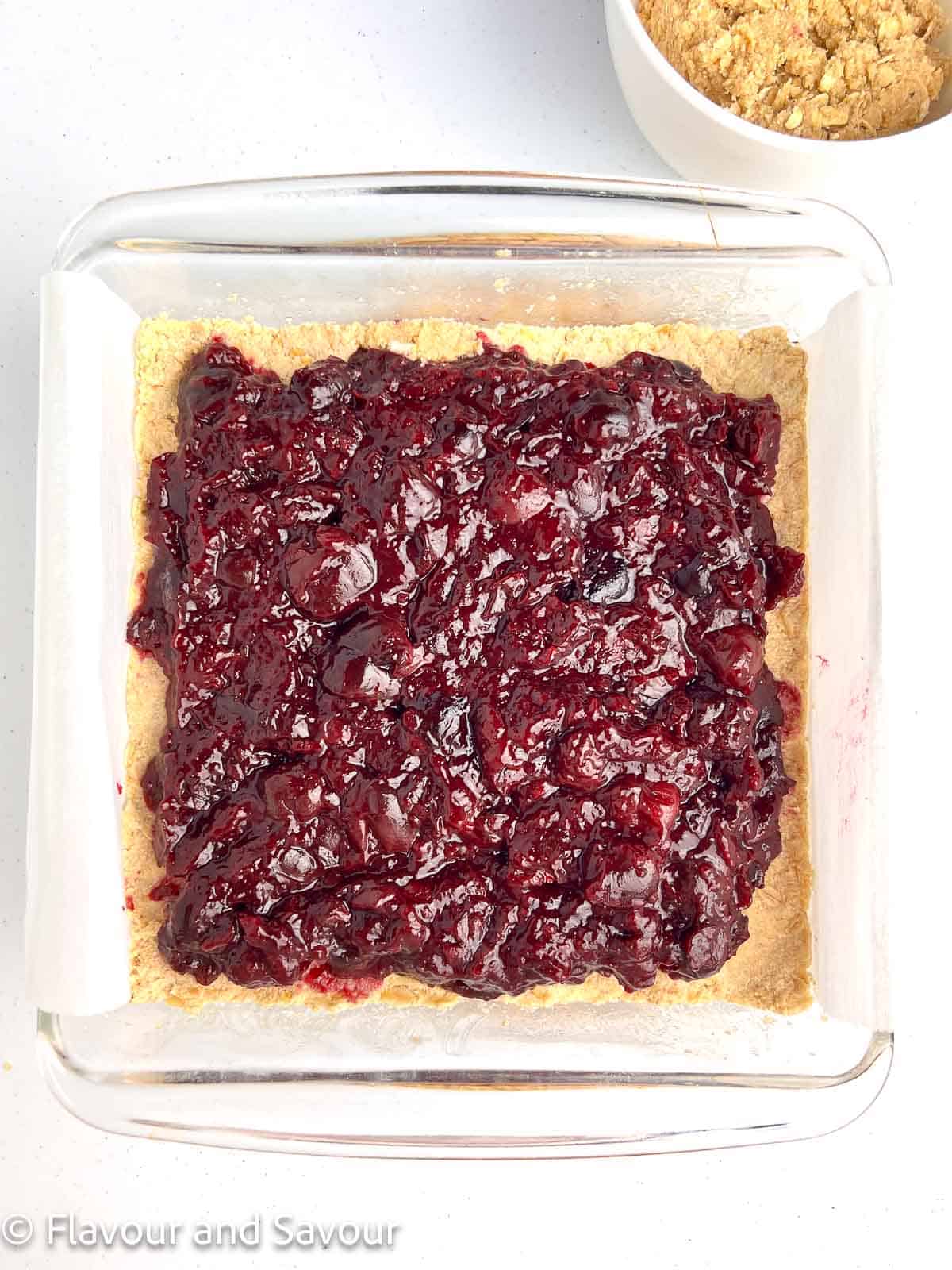 Cherry filling spread on top of baked crust for cherry pie oat bars.