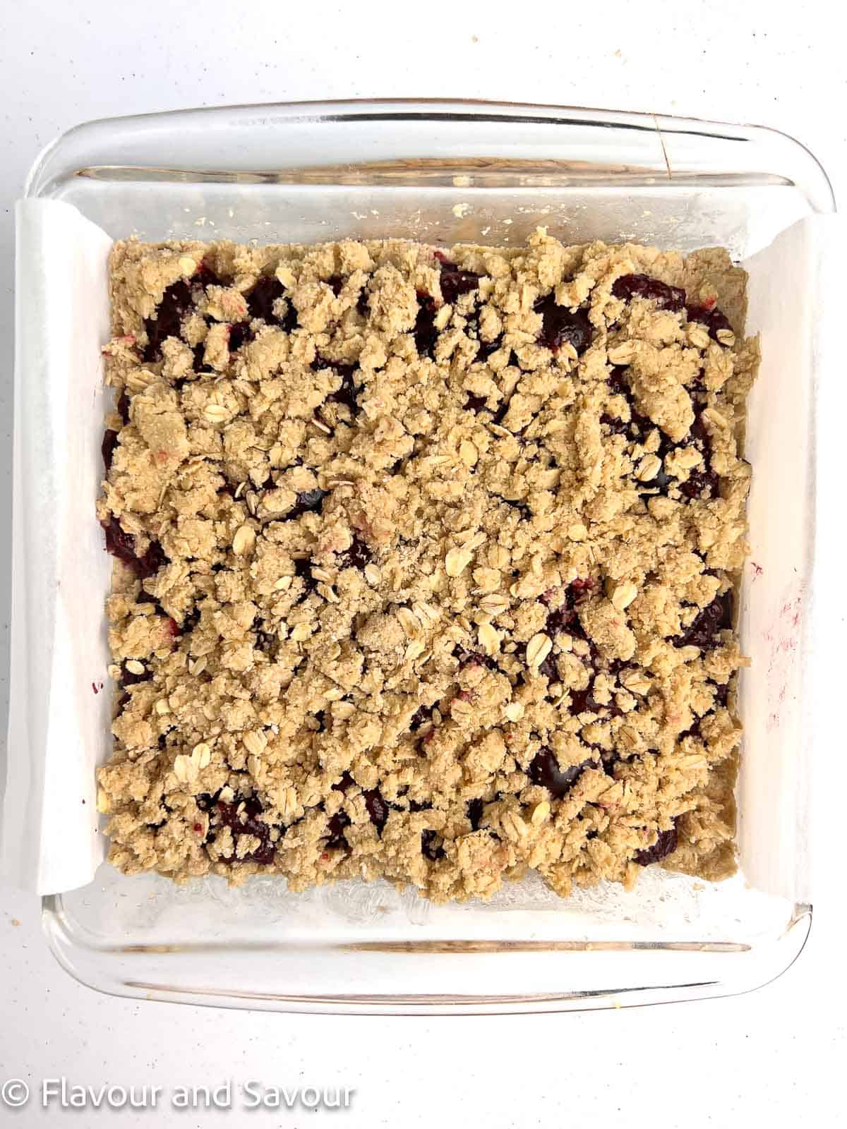 Crumble topping sprinkled on top of cherry filling to make cherry oatmeal crumble bars.