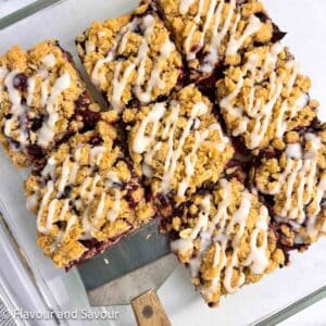 Cherry pie oatmeal crumble bars sliced into squares in a glass dish.