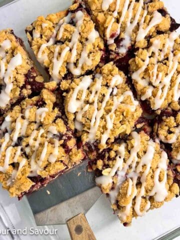 Cherry pie oatmeal crumble bars sliced into squares in a glass dish.