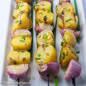 Grilled skewered potatoes and onions garnished with fresh chives.