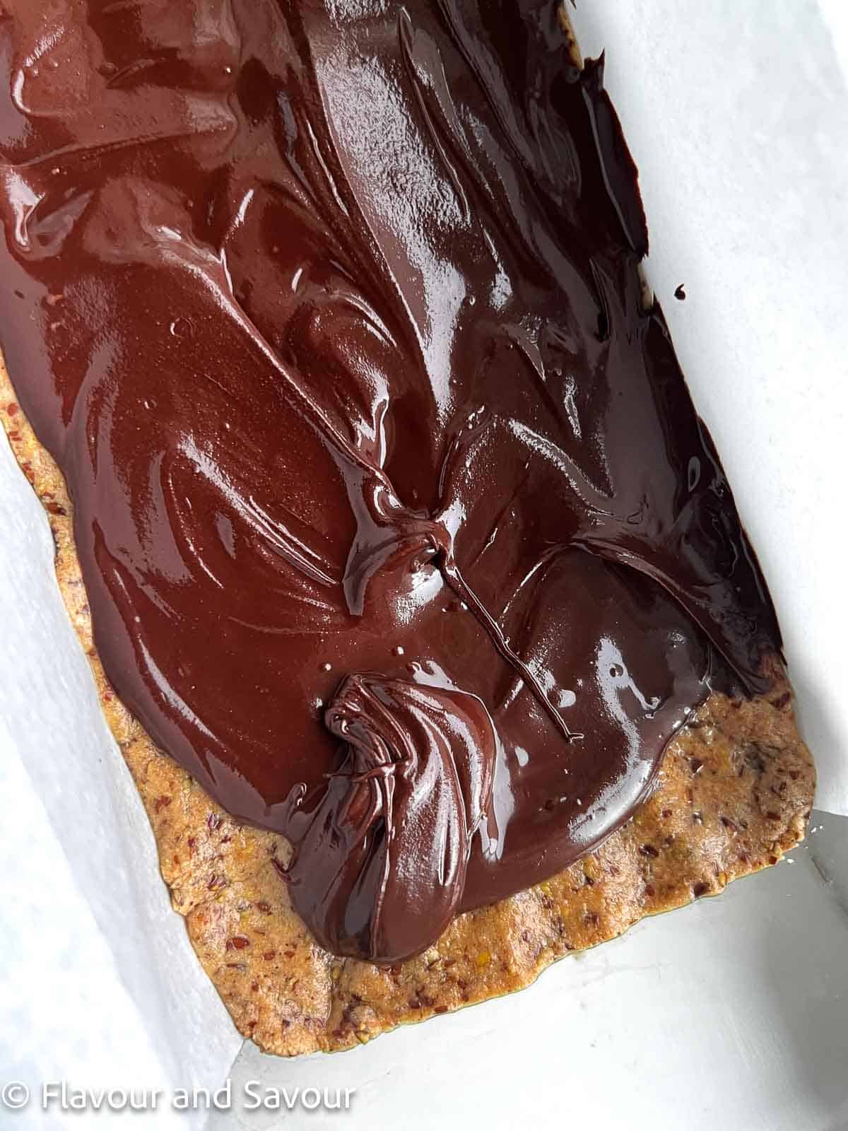 Melted chocolate layer on peanut butter collagen bars in a loaf pan.