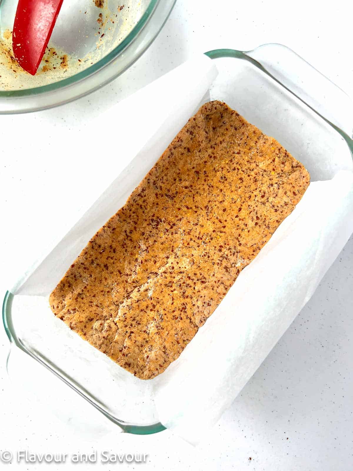 Peanut butter collagen batter pressed into a parchment paper lined loaf pan.