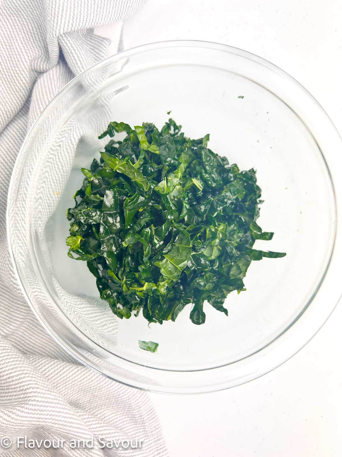 Finely chopped and massaged Tuscan Kale in a glass bowl.