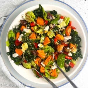Kale Salad with air fried sweet potatoes, red pepper, feta cheese, sunflower seeds and Medjool dates in a bowl.