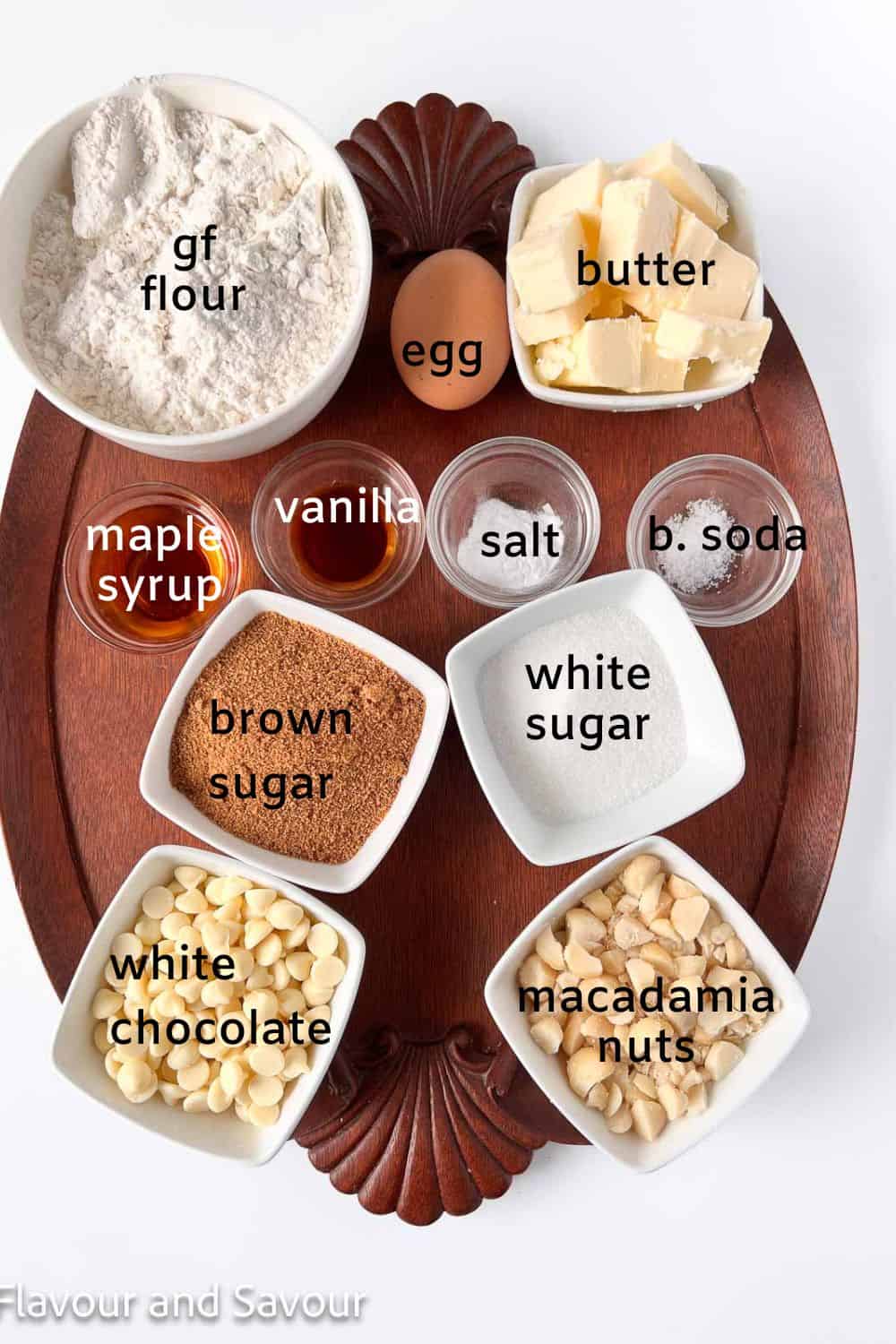 Ingredients for white chocolate macadamia nut cookies: gf flour, egg, butter, brown sugar, white sugar, maple syrup, vanilla, salt, baking soda, white chocolate and macadamia nuts.