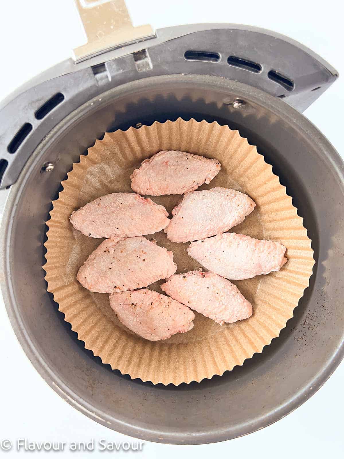 Chicken wings in an air fryer basket.