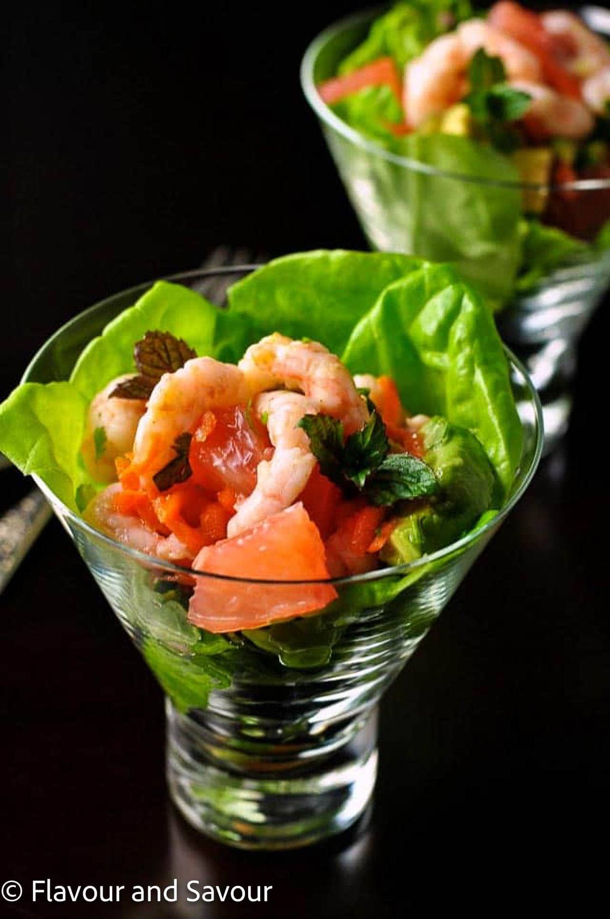 Thai-inspired shrimp salad with grapefruit, blood orange and mint leaves in a glass dish.