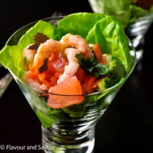 Thai-inspired shrimp salad with grapefruit, blood orange and mint leaves in a glass dish.
