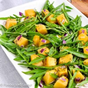 A platter with arugula leaves, cantaloupe cubes and finely chopped red onion tossed with poppyseed dressing.