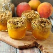 Small jars of mini peach crisp on a board.