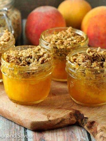 Small jars of mini peach crisp on a board.