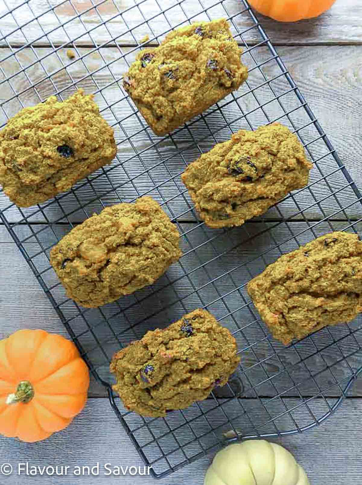 Overhead view of six mini pumpkin loaves on a wire rack.