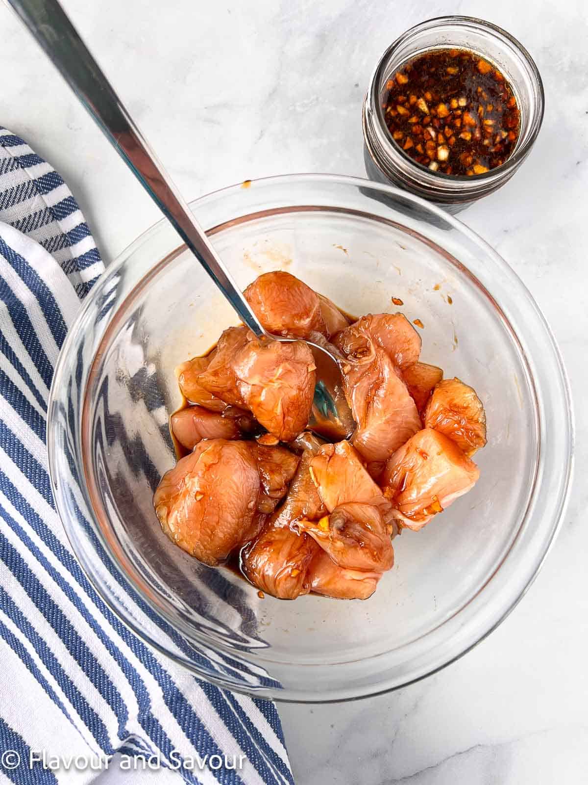 Chicken cubes with teriyaki marinade in a glass bowl.